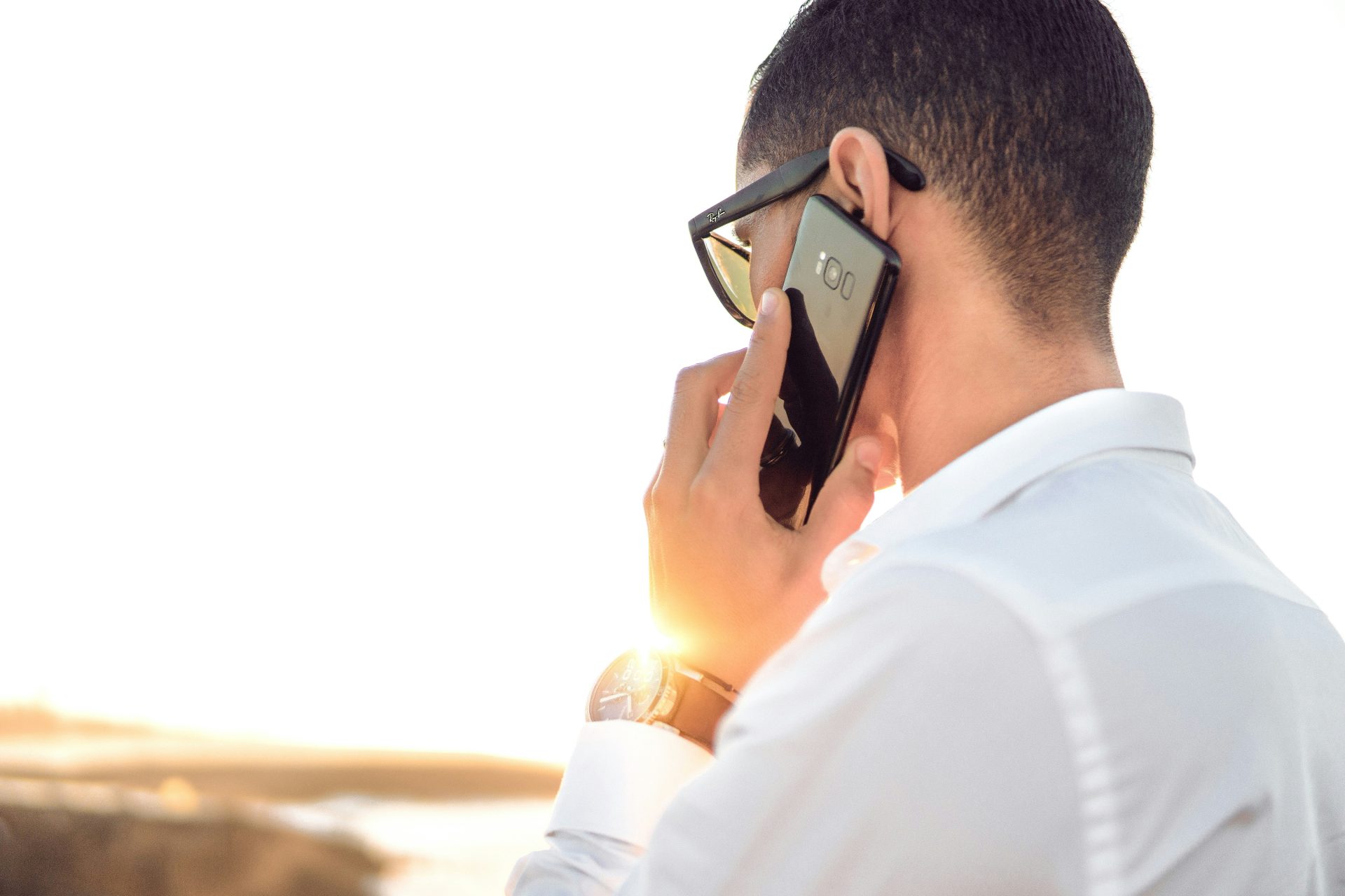 Man on phone with sunlight behind.